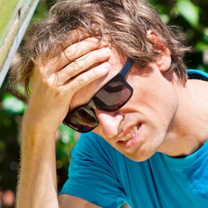 Man sitting forward rubbing temples due to a migraine