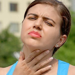 Woman on couch coughing into hand